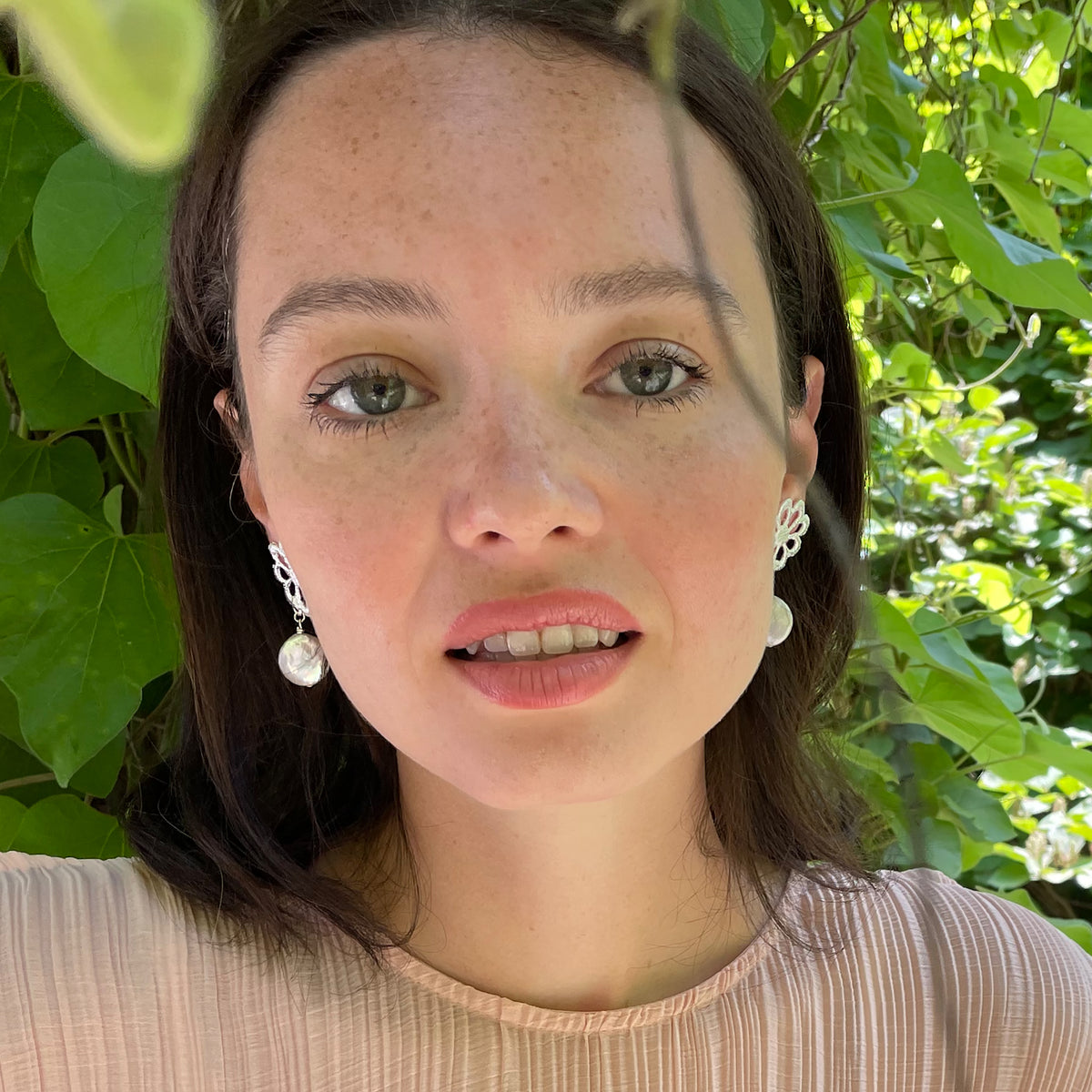 Model wearing baroque coin pearl earring with flower lace in sterling silver.