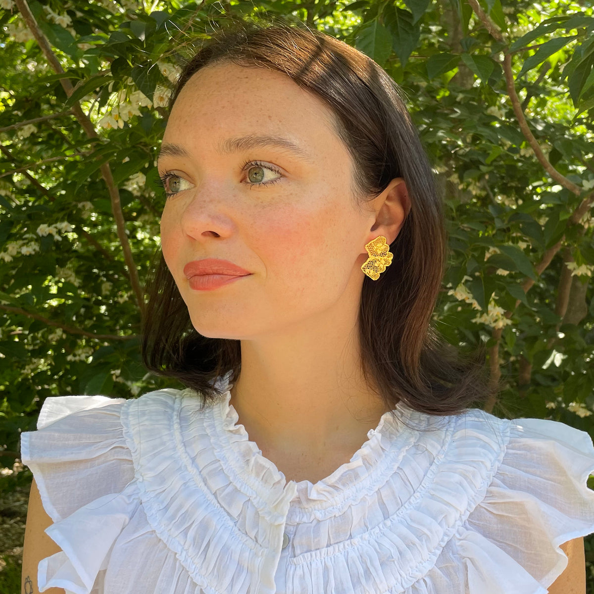 Audra lace stud earrings in 24k gold on model.