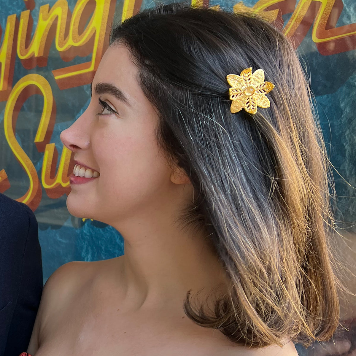 Beatrix lace flower barrette in 24k gold with Topaz stone worn by a model.