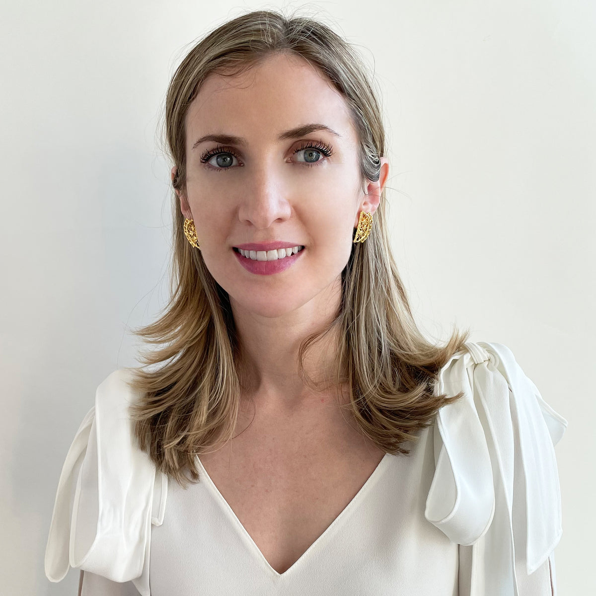 Half-moon lace stud earrings in 24k gold on a model.