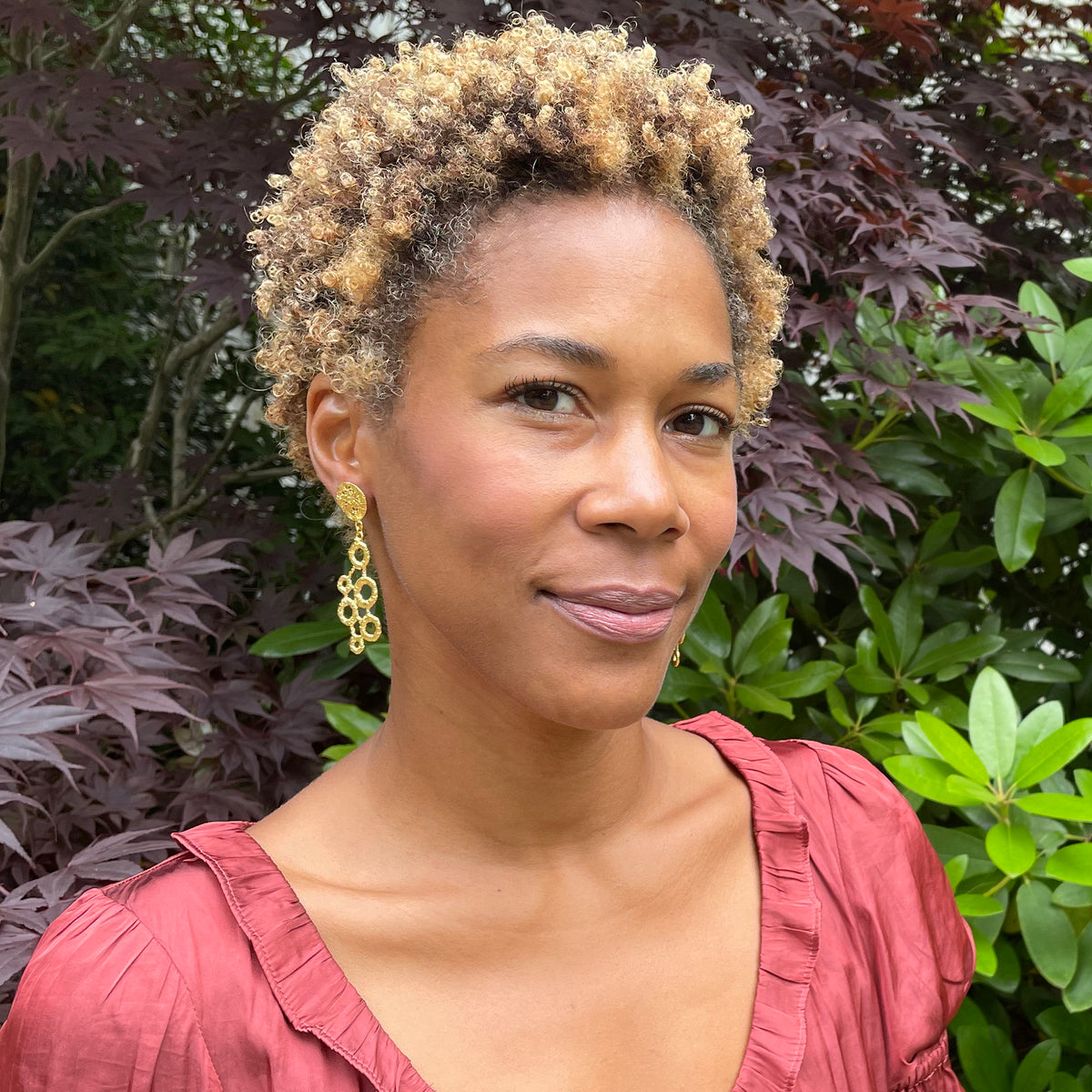 Dana circular lace dangle earrings in 24k gold on a model.