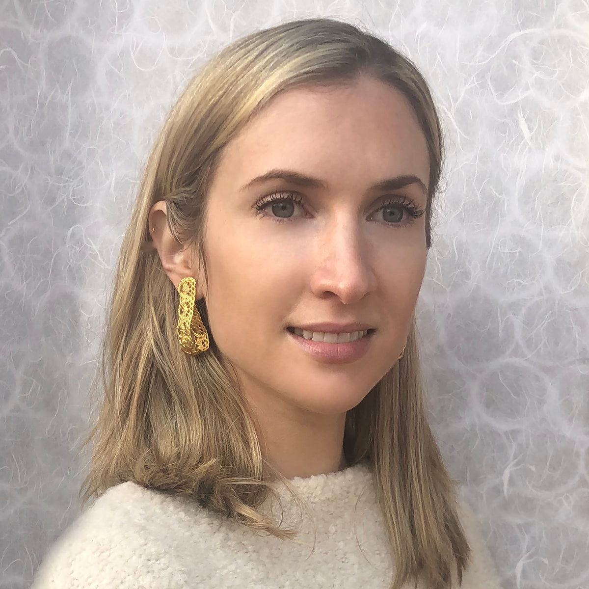 Model showing favorite earrings made from French 1920s lace forming a loop and solidified in 24k gold.