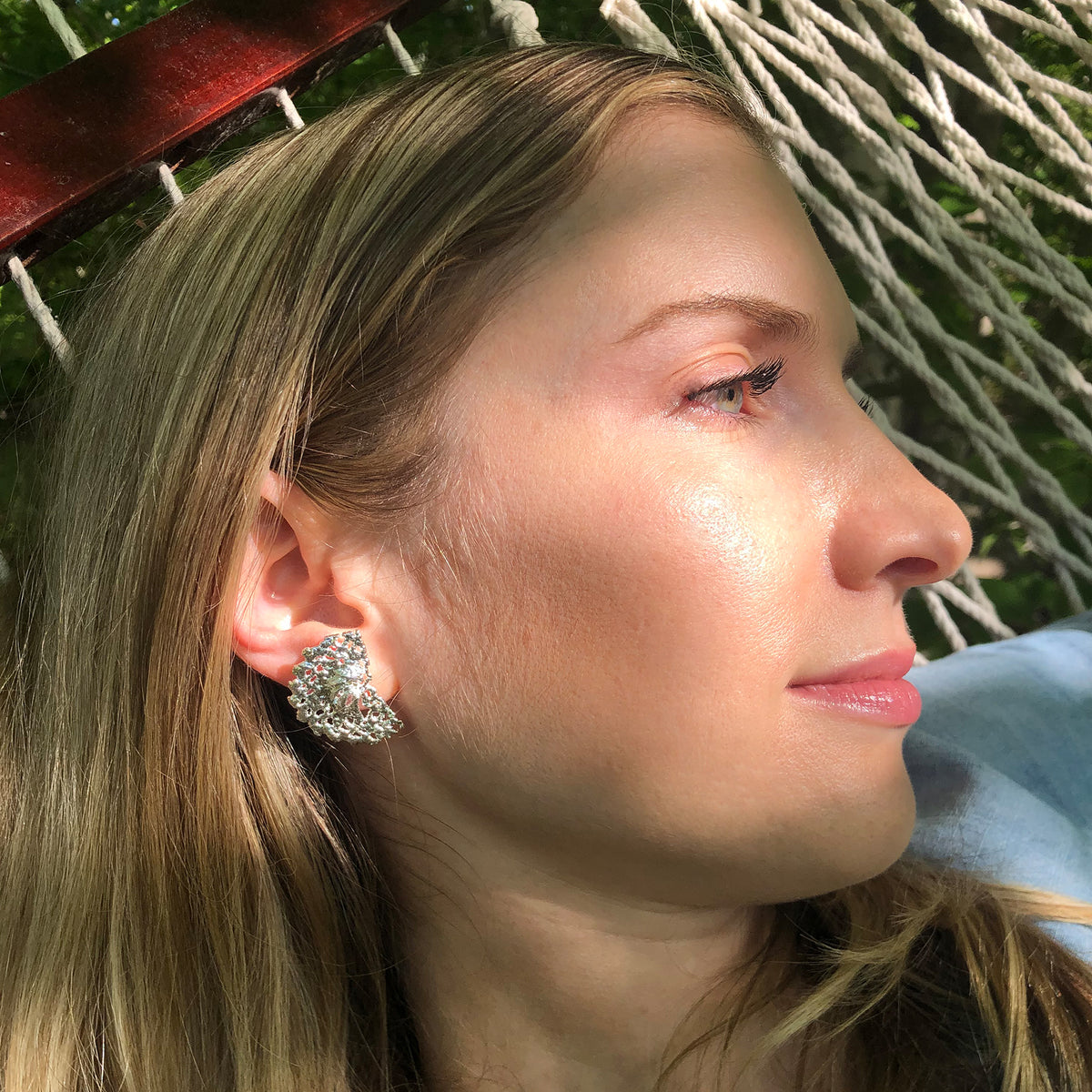 Model wearing half moon stud earrings made from Swedish lace dipped in sterling silver.