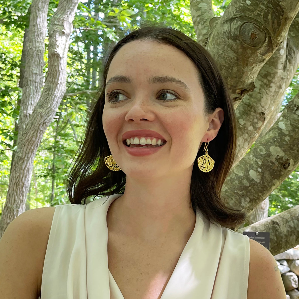 Fan shaped lace earrings in 24k gold on model.