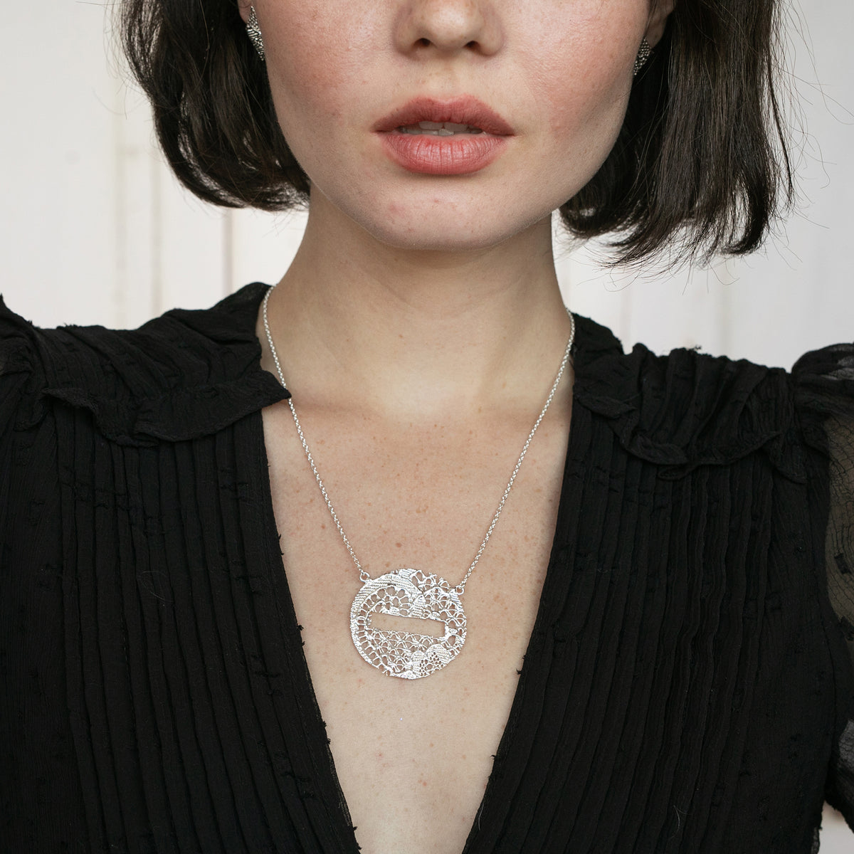 Model showing Intricate lace necklace in the shape of a DO NOT ENTER traffic sign in sterling silver.