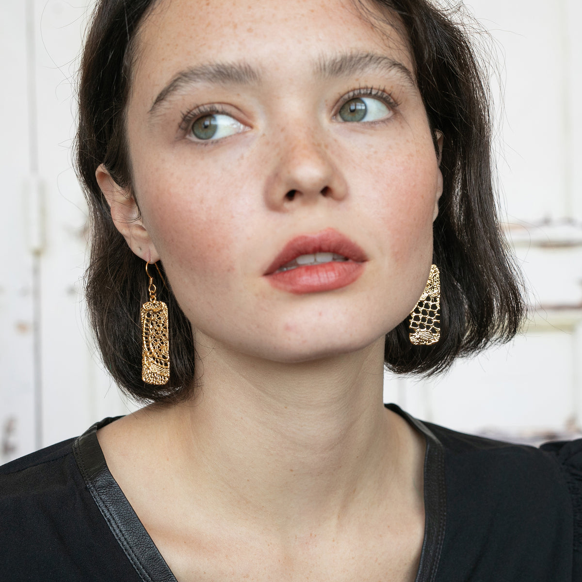 Brilliant Rectangular 24k gold Lace Earrings with French hooks worn by a model.