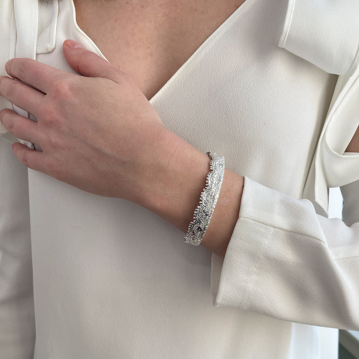 Lace bangle bracelet in sterling silver worn by a model. Signed and numbered in the back.