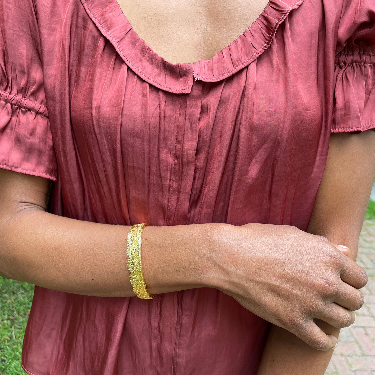 Lace bangle bracelet in 24k gold worn by a model. Signed and numbered in the back.