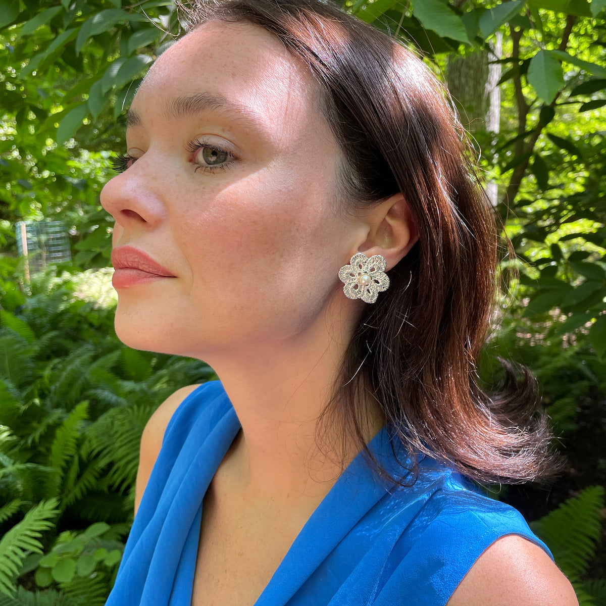 Pearl stud earrings with lace flower in sterling silver on model.