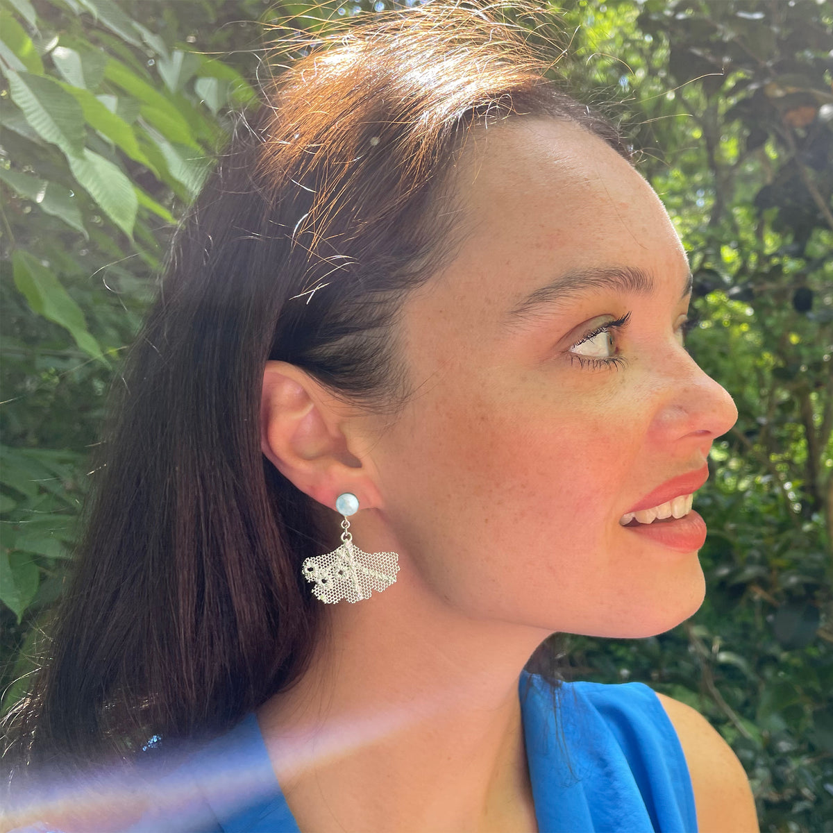 Model wearing pearl earrings with lace in the shape of a ginkgo leaf in sterling silver.