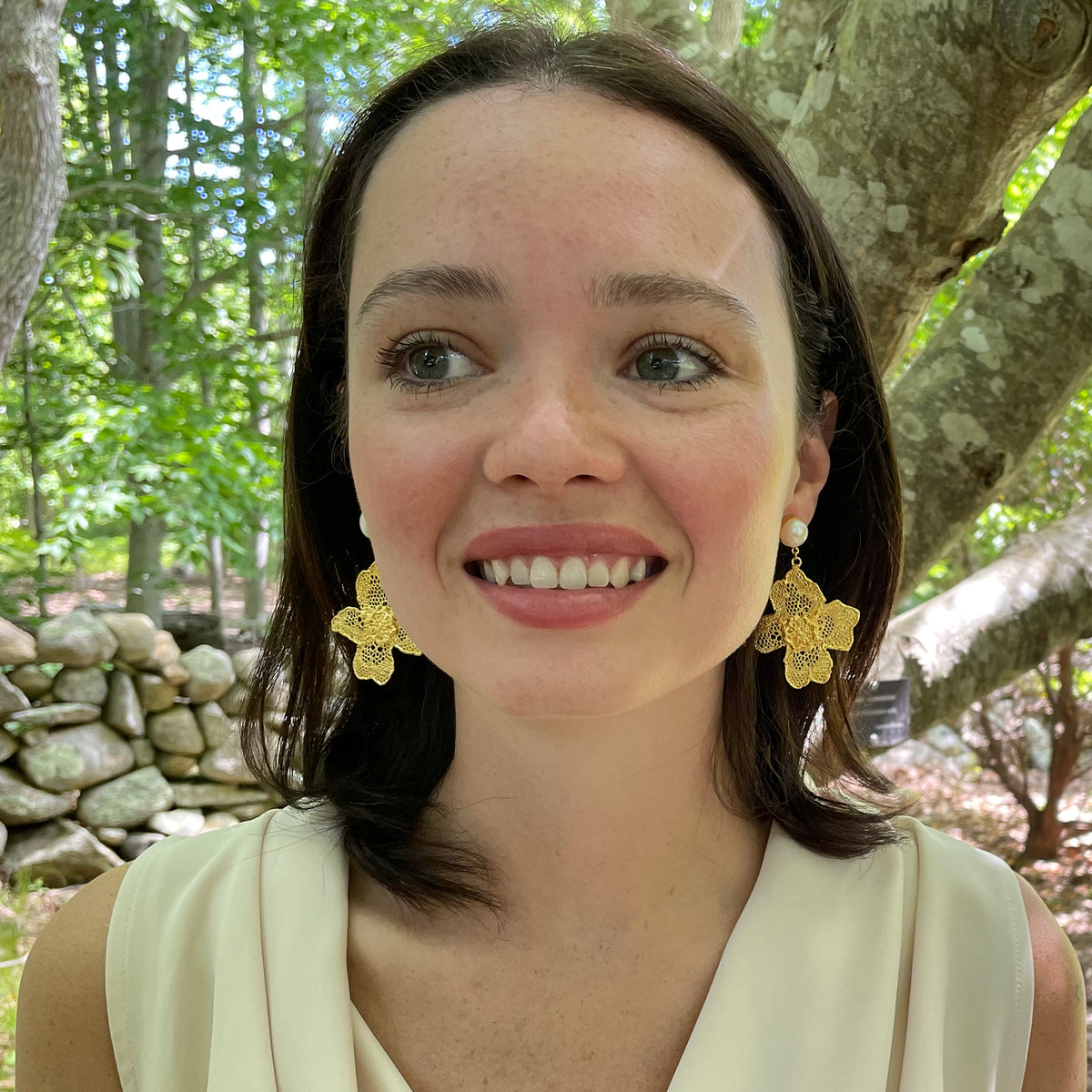 Model wearing dangle pearl earrings with large lace flower in 24k gold.