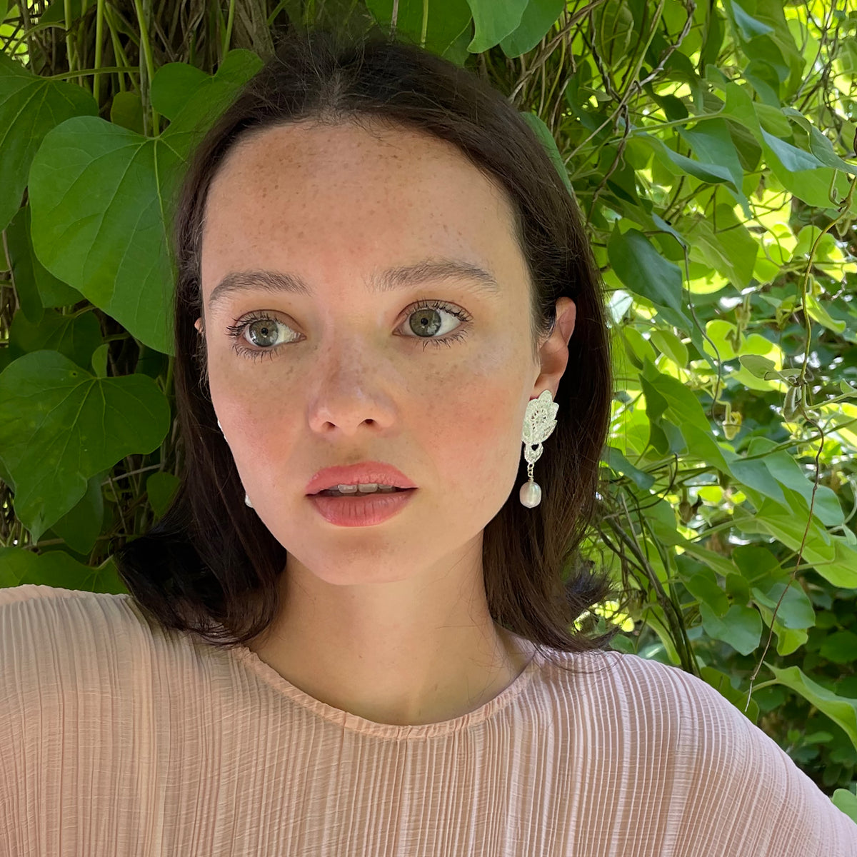 Model wearing baroque pearl earrings with lace rose in sterling silver.