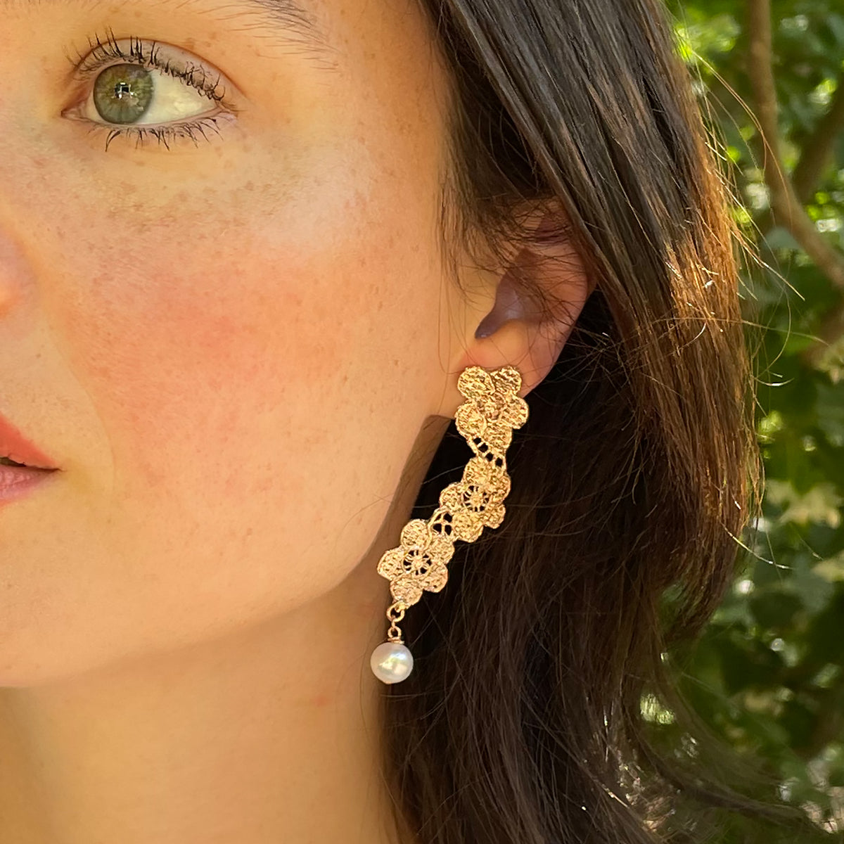 Model showing pearl earrings with lace flower garland dipped in rose gold.