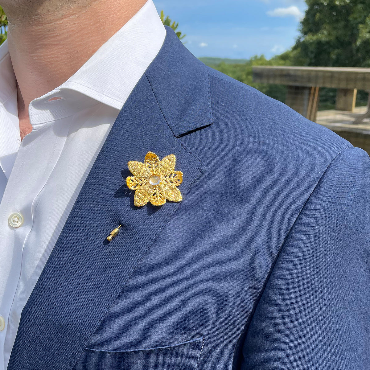 Model wearing Lapel pin 24k gold lace flower with 10mm white Topaz.