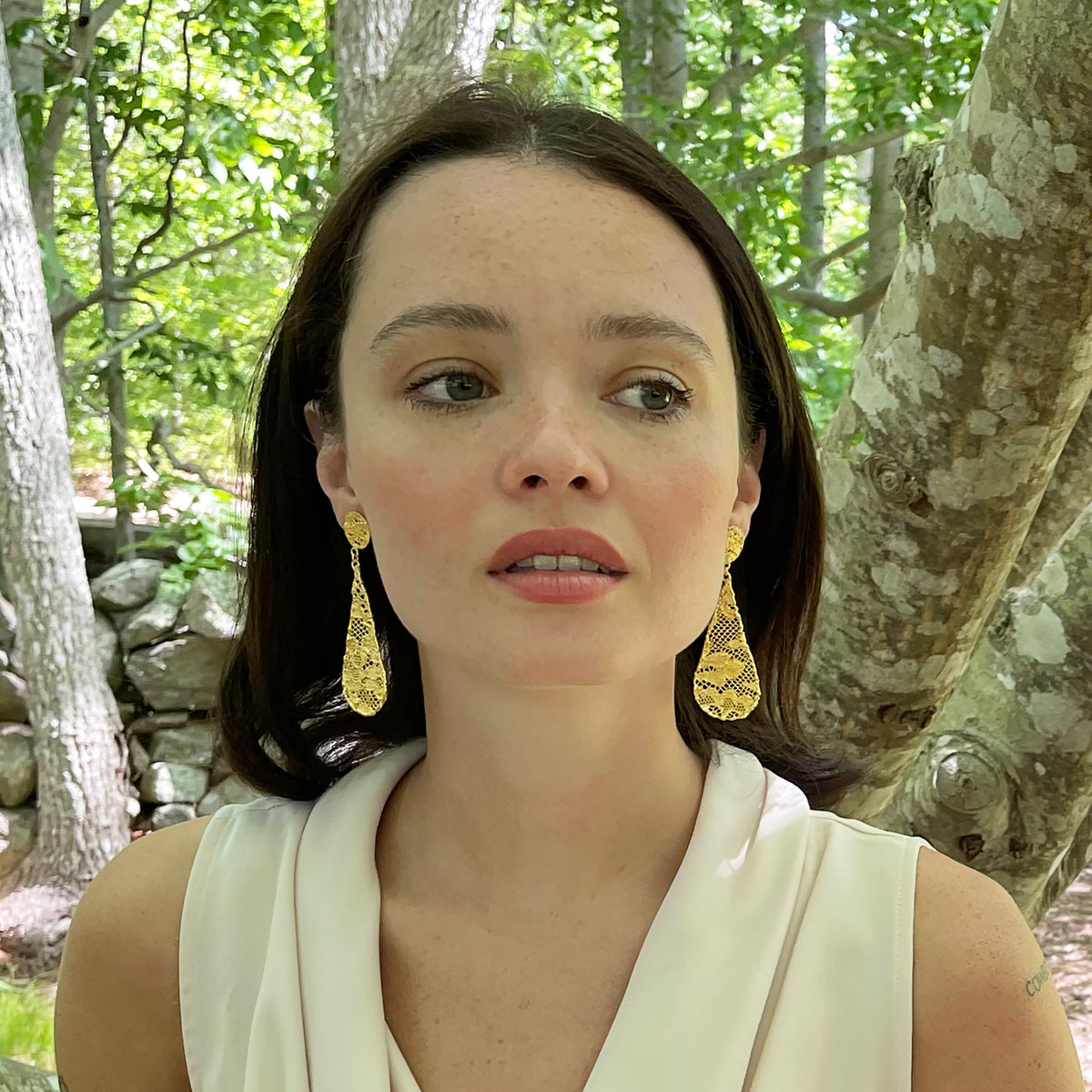Teardrop lace earrings dipped in 24k gold on model.