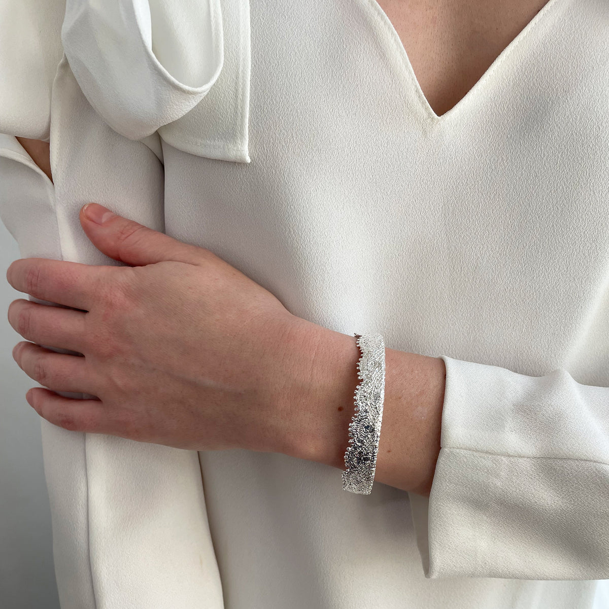 Lace bangle bracelet in sterling silver worn by a model. Signed and numbered in the back.