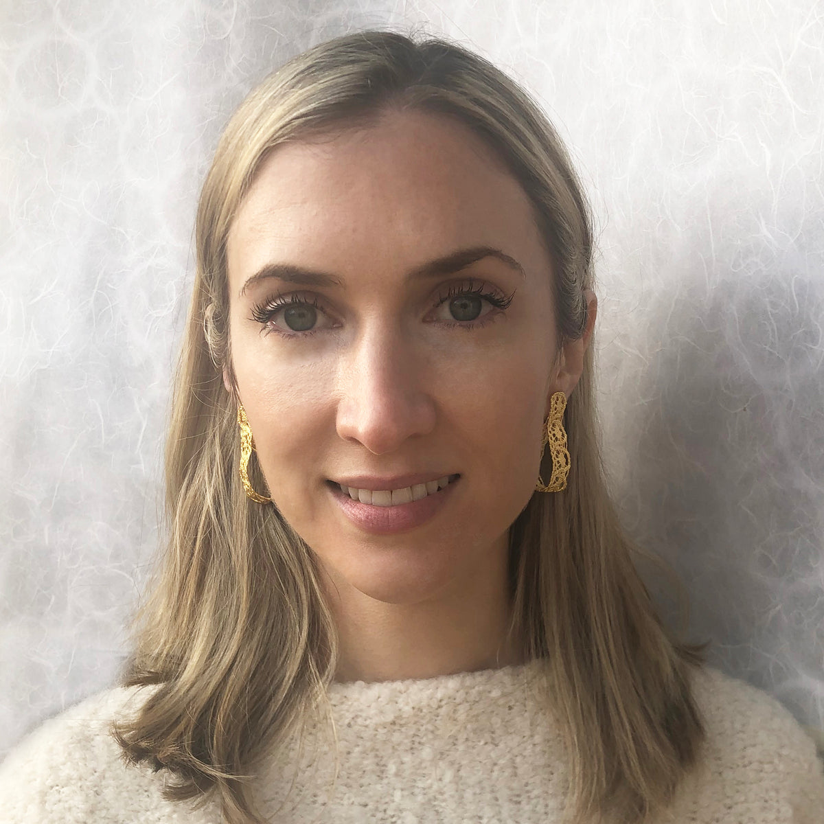 Model showing favorite earrings made from French 1920s lace forming a loop and solidified in 24k gold.