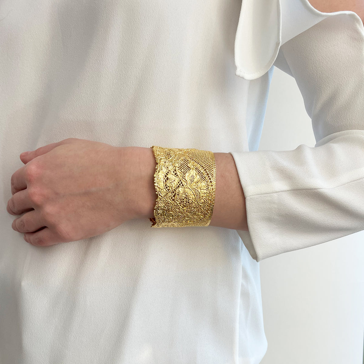 Model wearing intricate lace cuff bracelet in 24k gold.
