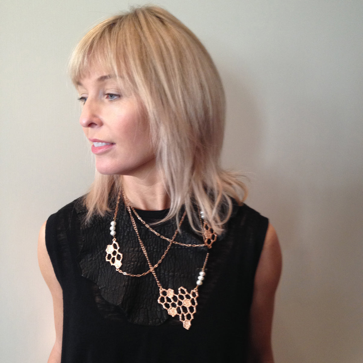 Honeycomb lace pendant necklace in rose cold with white fresh water pearls on a model.