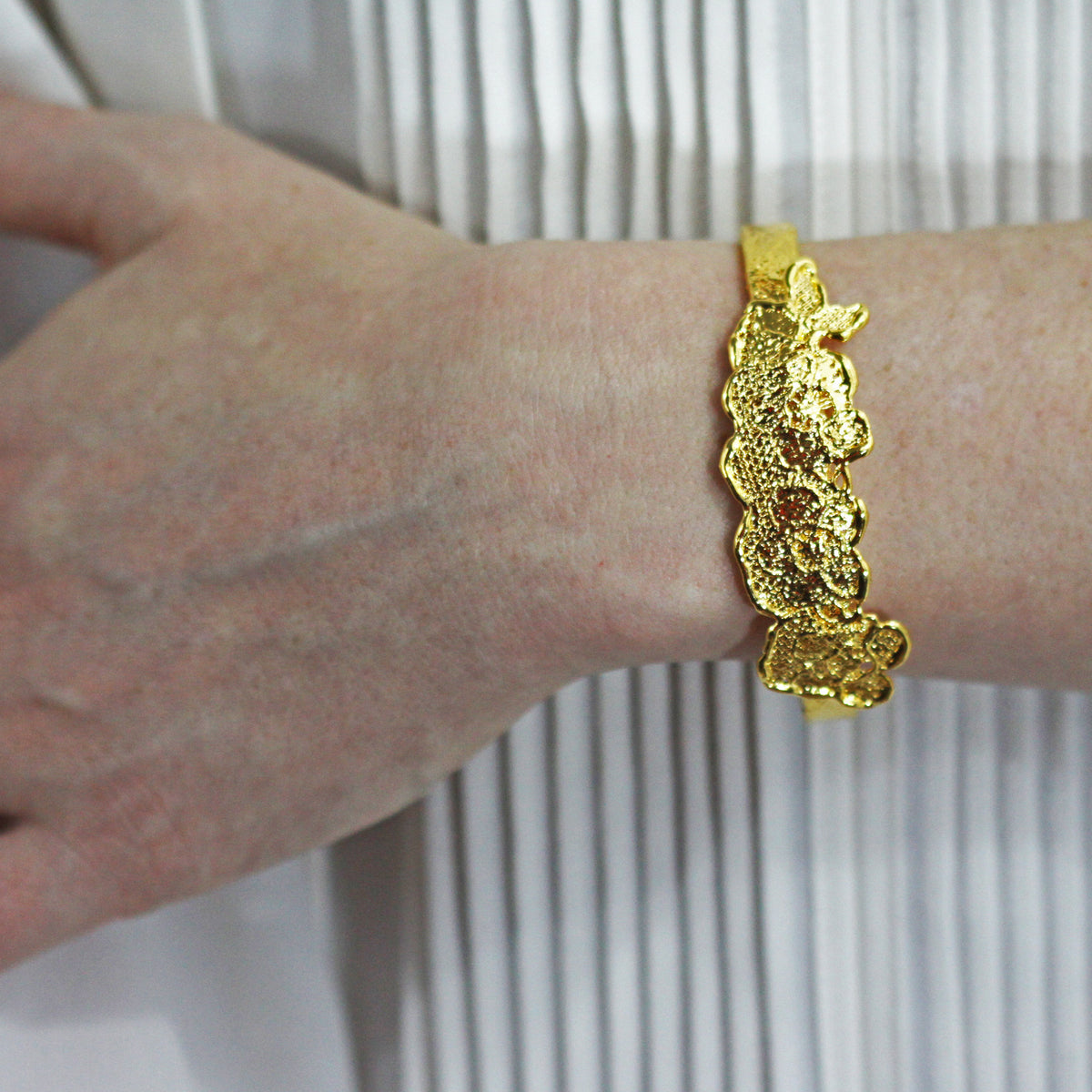 Alex lace bracelet in brilliant 24k gold on a model.