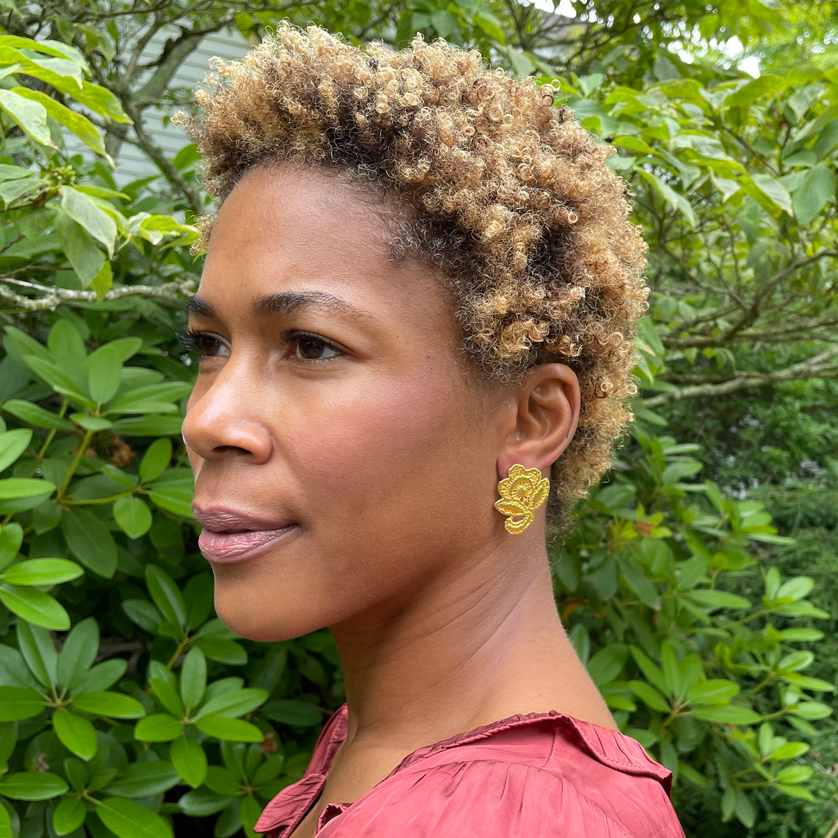 Flower stud earrings made from American lace dipped in 24k gold on a model.