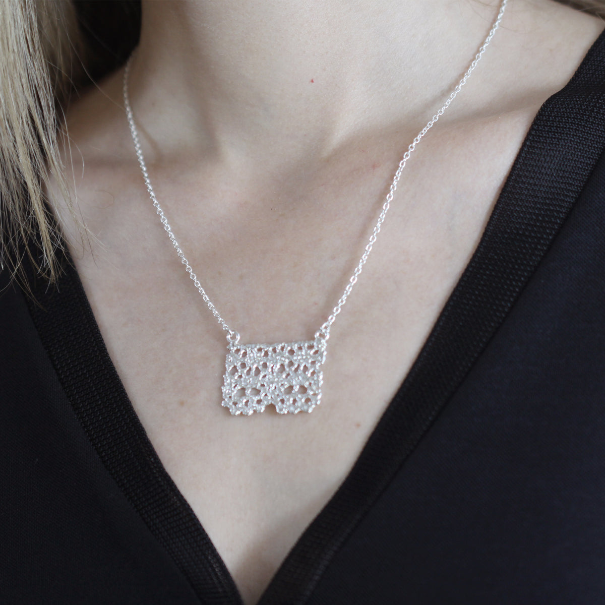 Swedish lace pendant necklace dipped in sterling silver on model.