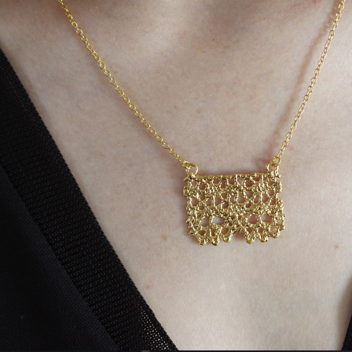 Swedish lace pendant necklace dipped in 24k gold on a model.