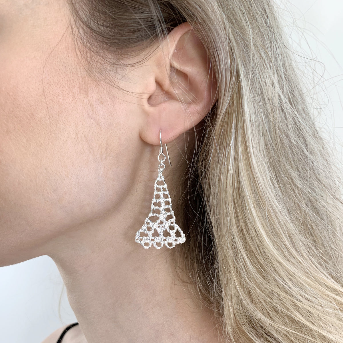Model wearing silver teardrop earrings made from 1940s Swedish bobbin lace dipped in sterling silver.