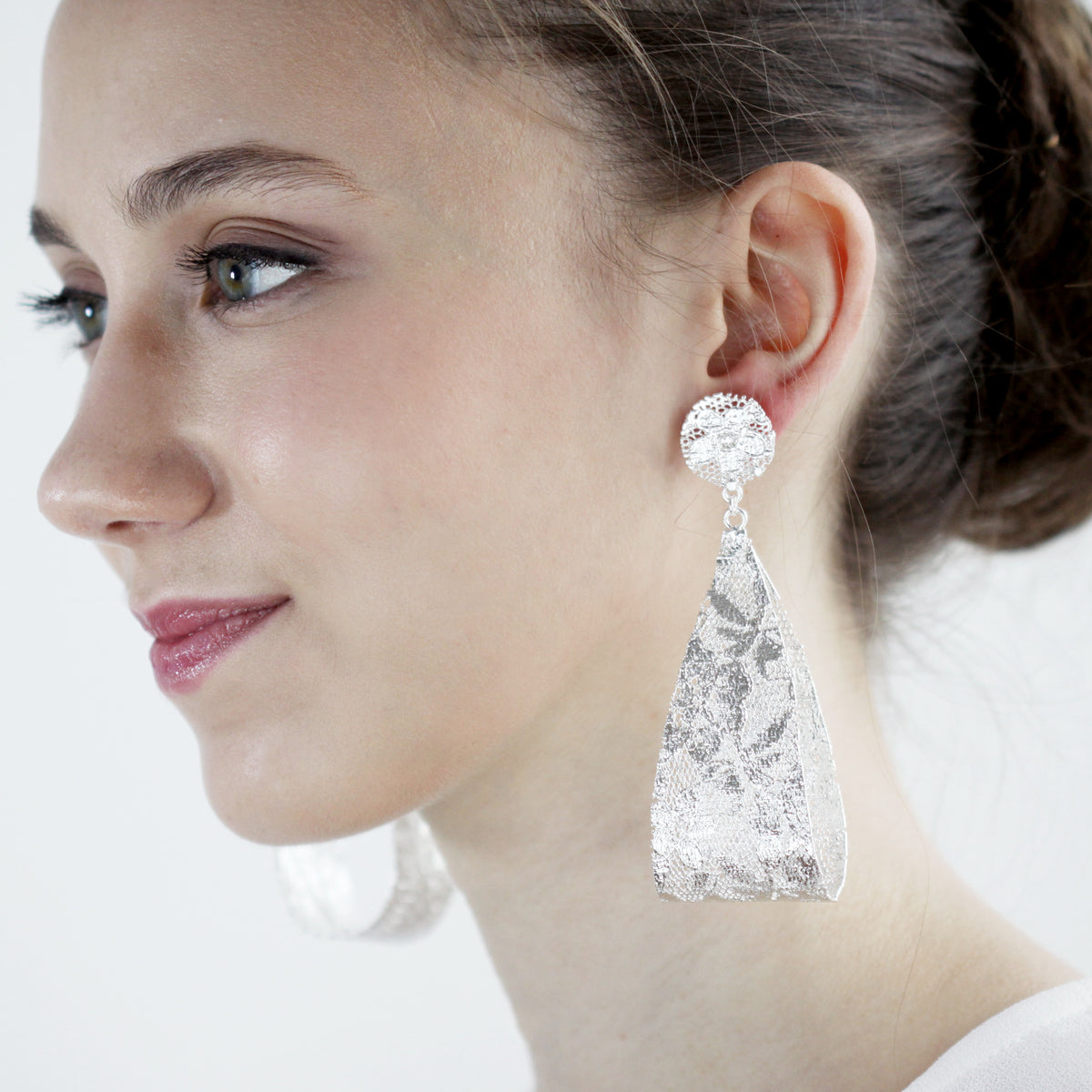 Camille, large lace teardrop earrings in sterling silver on a model.