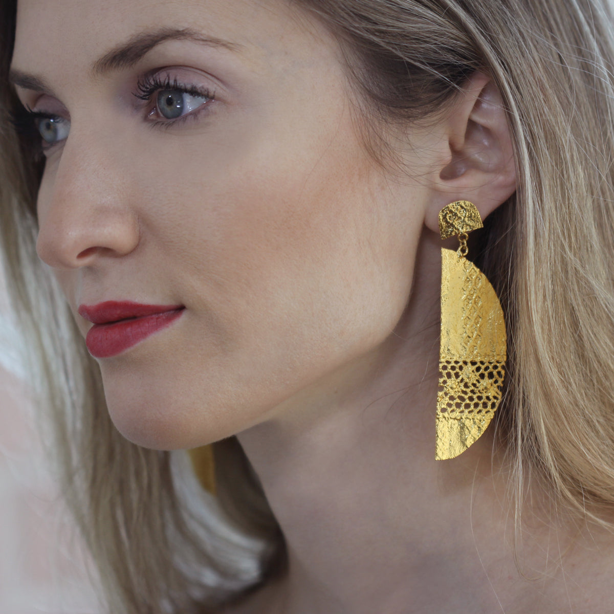 Model wearing half moon lace earrings in 24k gold.