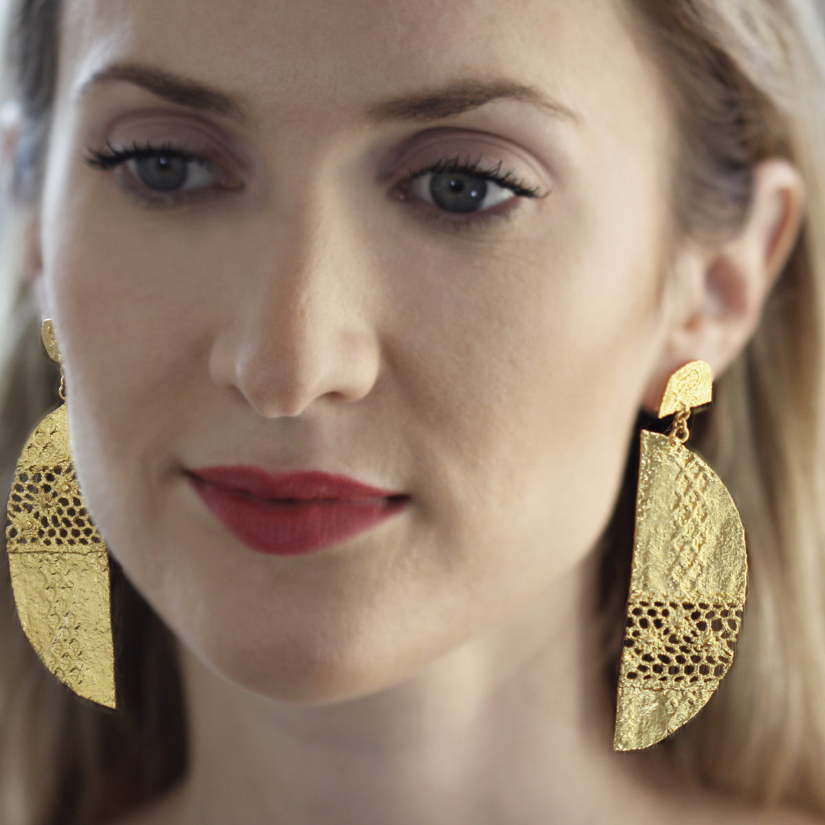 Model wearing half moon lace earrings in 24k gold.