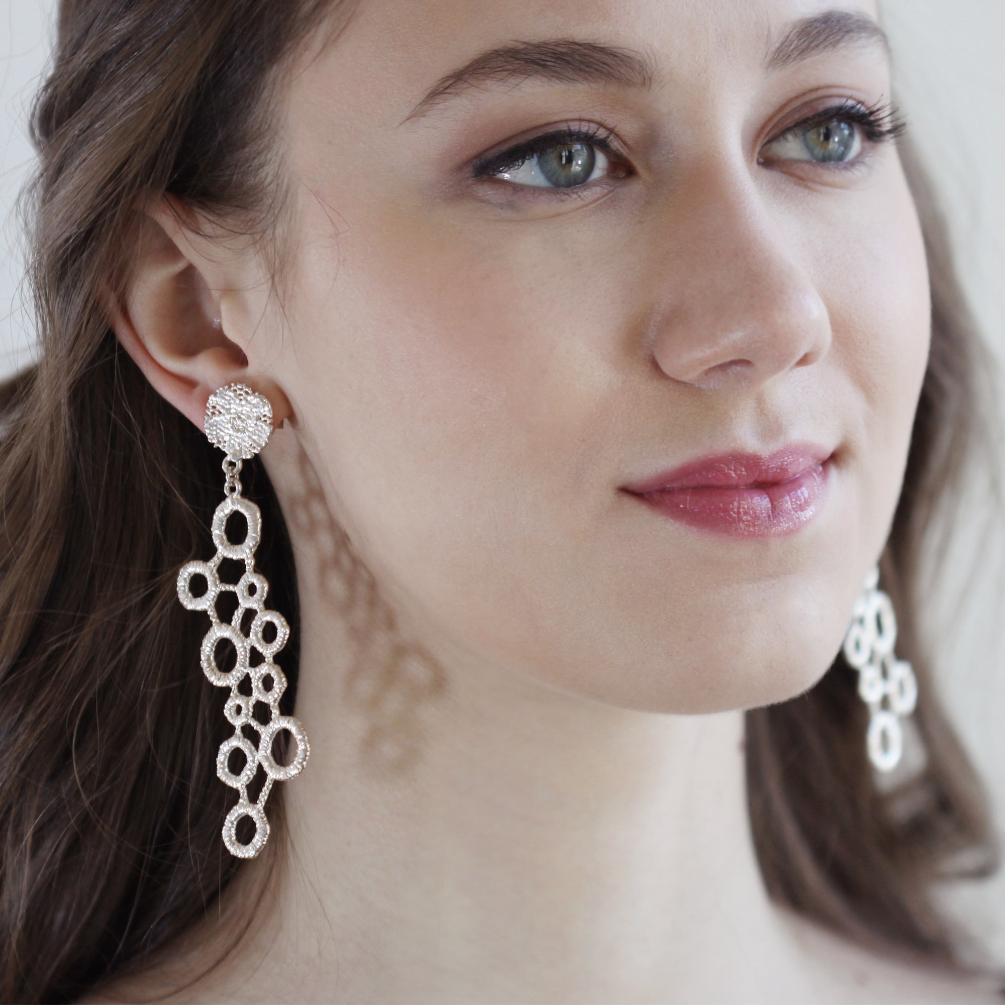 Large drop earrings made from circular lace dipped in sterling silver.