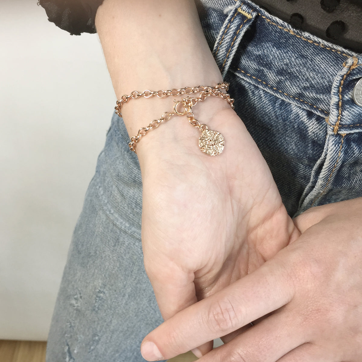 Showing the back of the chain bracelet with a small lace charm, all dipped in rose gold.