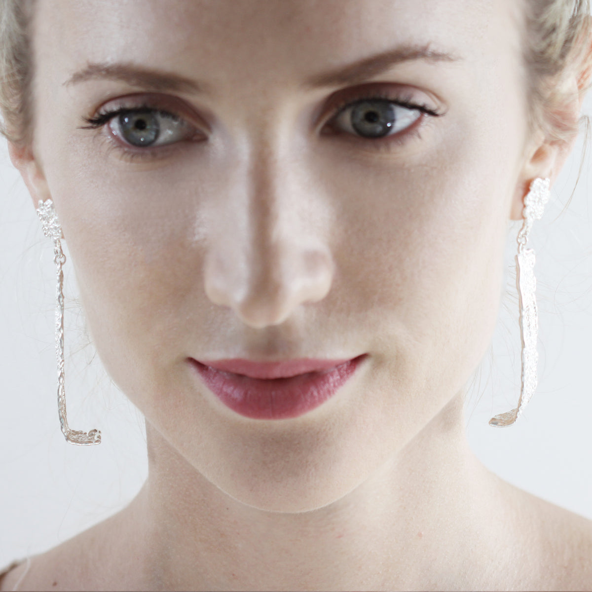 Long lace earrings with fine details in sterling silver worn by a model.