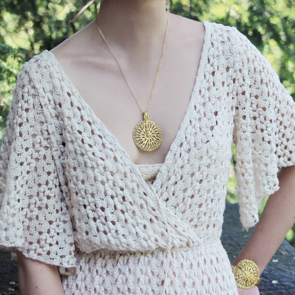 Rare round lace pendant necklace dipped in 24k gold worn by a model.