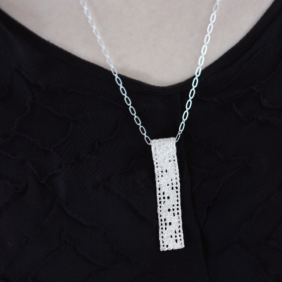 Lace pendant necklace solidified in sterling silver on model.