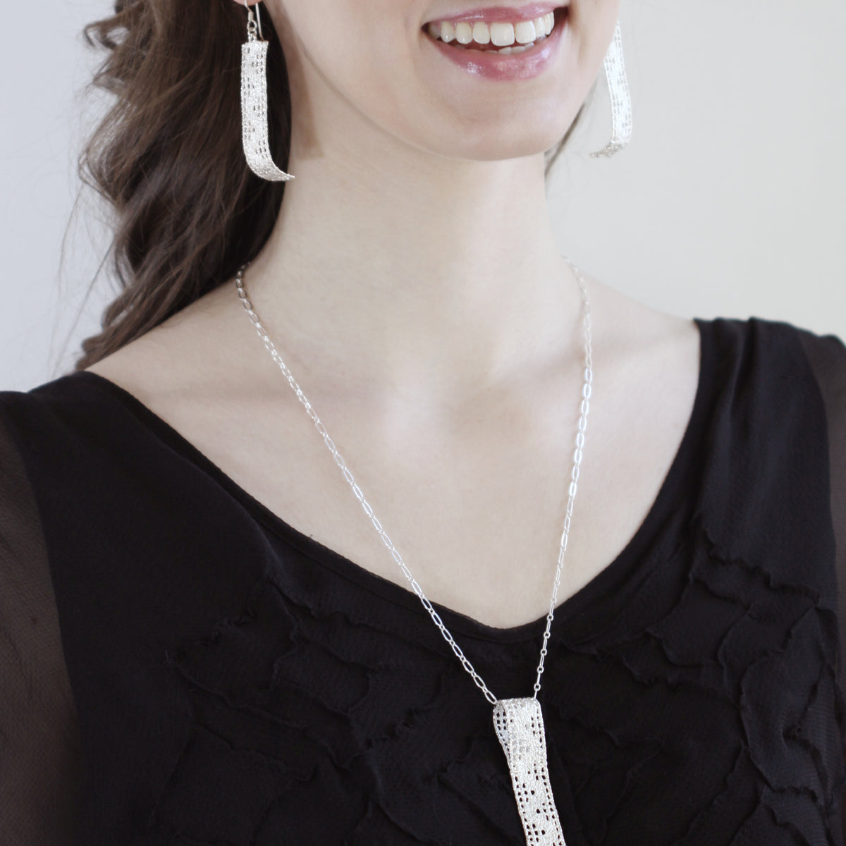Lace pendant necklace solidified in sterling silver on model.