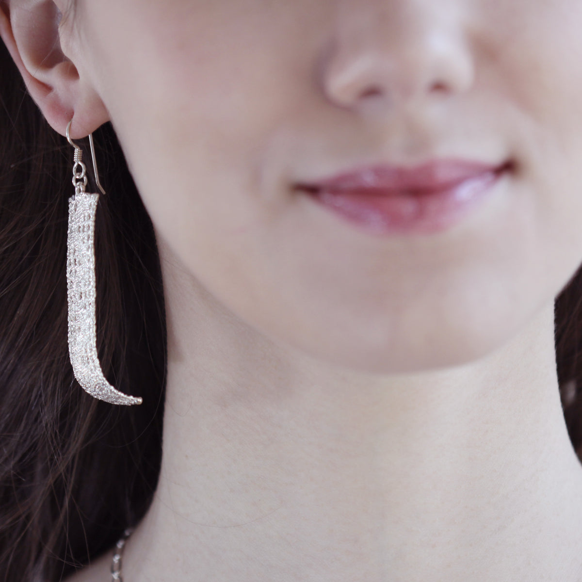 Long lace earring in sterling silver on a French wire worn by a model.